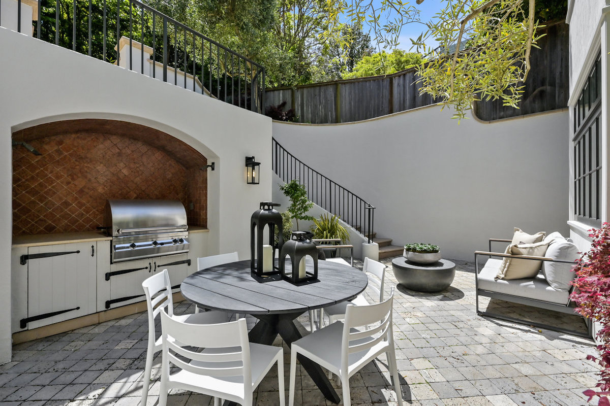 Directly outside the kitchen the outdoor patio with grill, seating areas and staircase up to terraced deep gardens